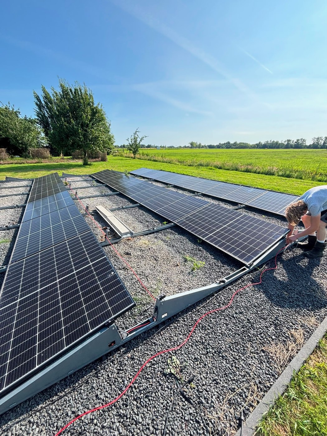 Een monteur van JTS Installatietechniek werkt aan de zonnepanelen in het veld in Nederhorst den Berg