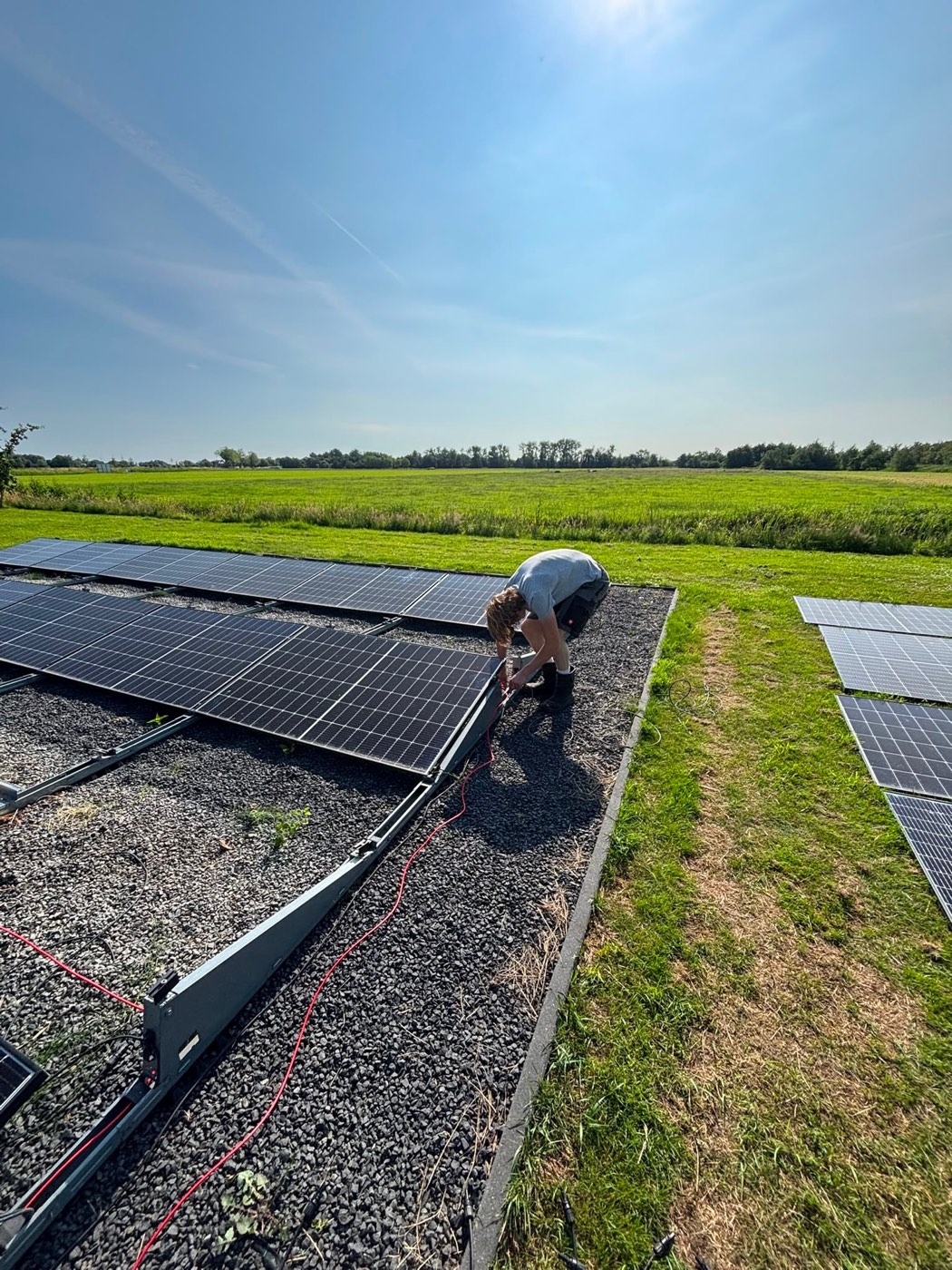 Een monteur van JTS Installatietechniek rondt de zonnepanelen in het veld af in Nederhorst den Berg