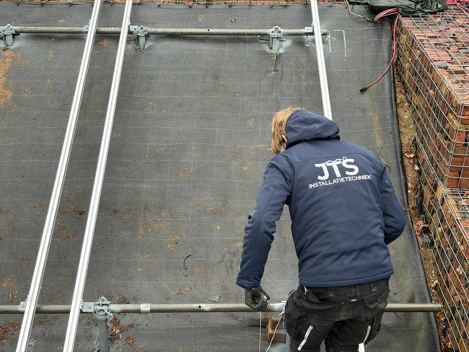 Monteur van JTS legt het montagesysteem op een plat dak