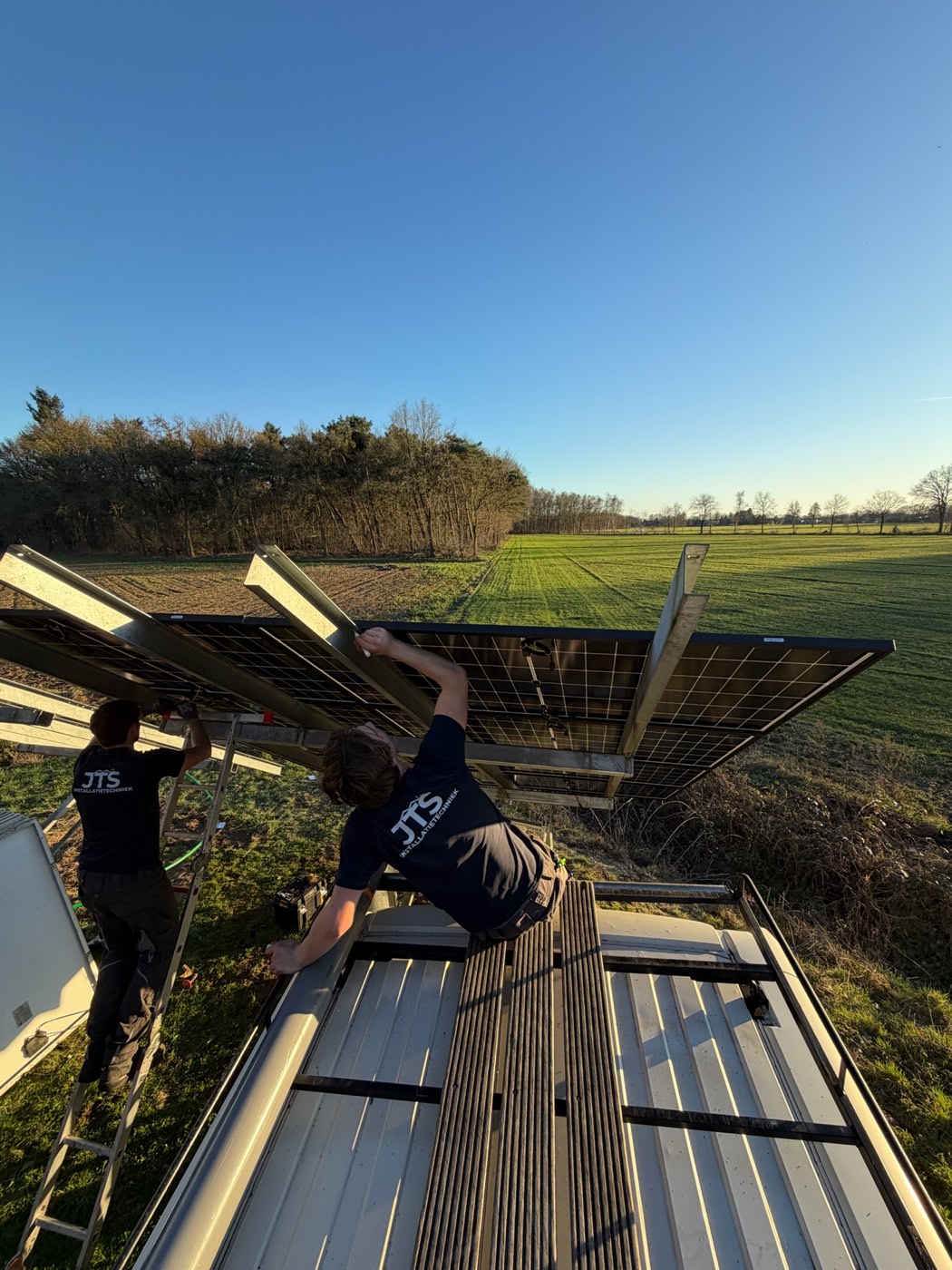 Twee JTS-monteurs bevestigen een zonnepaneel op de aangepaste constructie