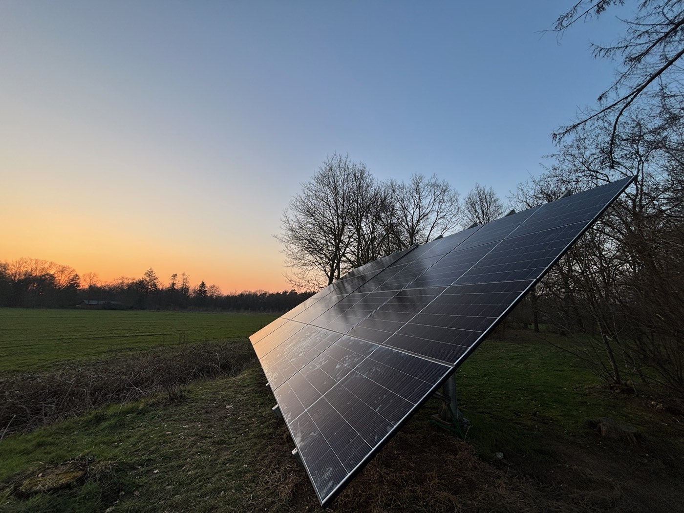 Zonnepanelen op een aangepaste grondopstelling in Brabant bij zonsondergang